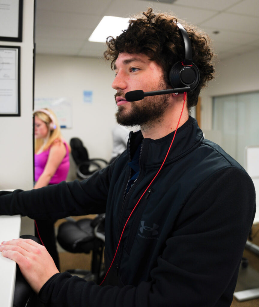 A young man with a headset looking at this computer screen. He is wearing all black.