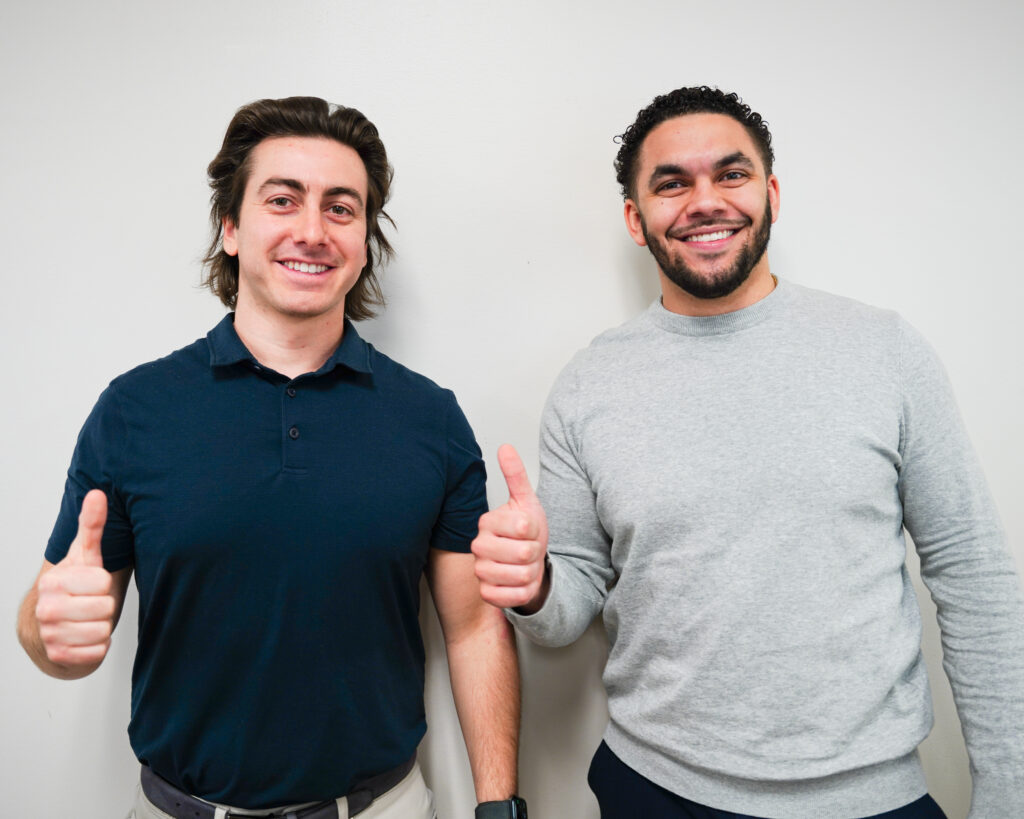 Two young men giving a thumbs up to the camera.